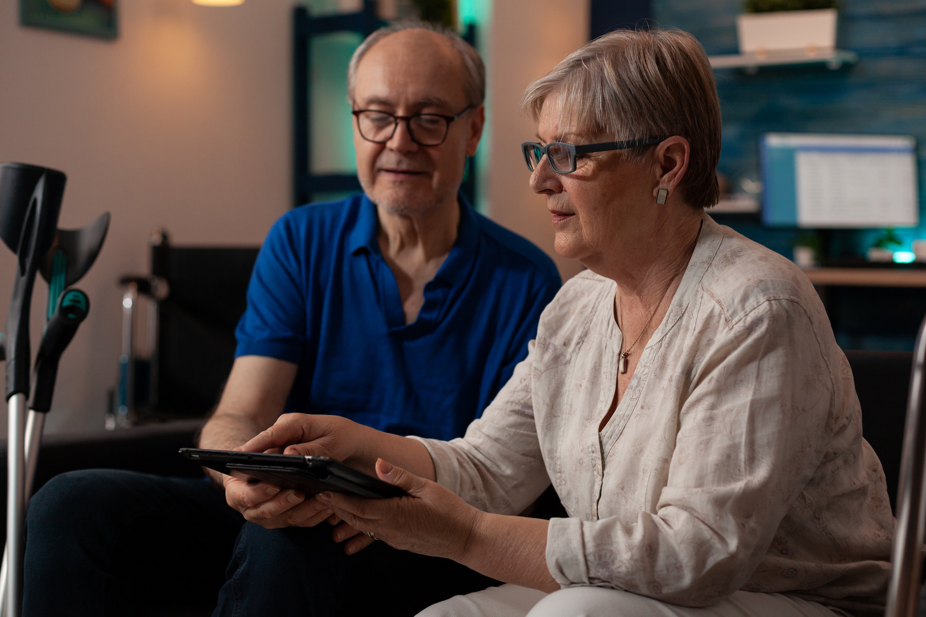 Aged couple looking at modern tablet in living room