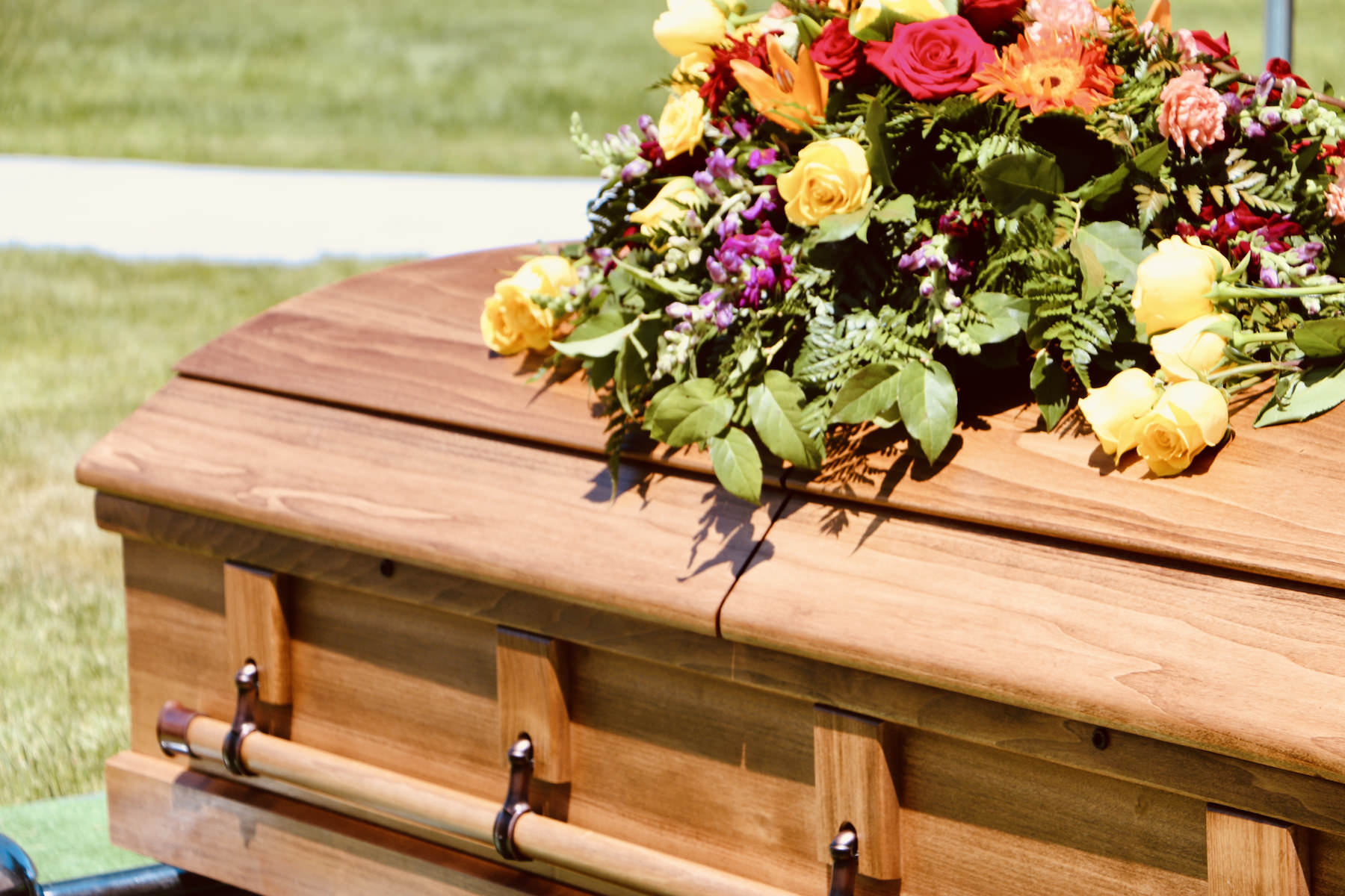 Lovely floral arrangement on wood casket. Mourning loss of loved one. Death of friend or family member. Funeral service. Saying goodbye.